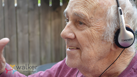 elderly man wearing headphones and smiling while listening to music