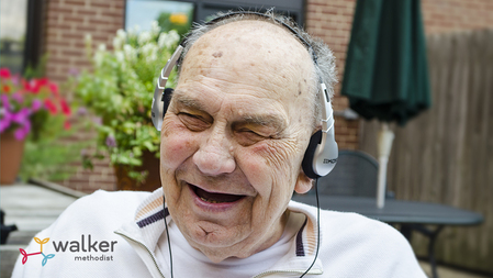 Les--elderly man wearing headphones and smiling while listening to music