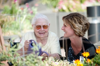 Long term care resident being helped with watering flowers