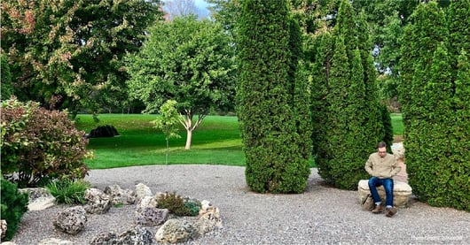 Man in jacket sits on rock in Lyndale Rose Garden Minneapolis