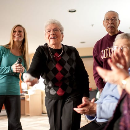 Senior woman plays video games as family claps