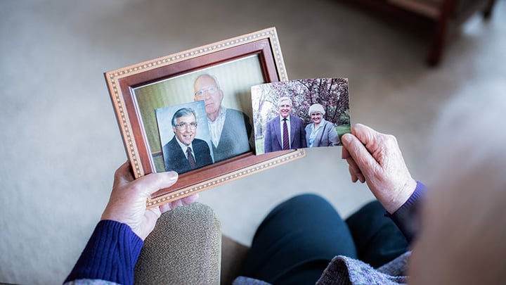 Shelley Wiggins holding framed photos of husband Chuck