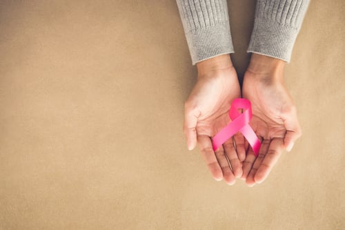 shot looking down at open hands holding a pink ribbon