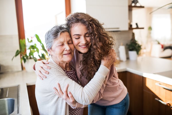 granddaughter hugging grandma in kitchen