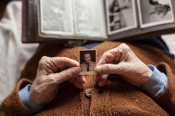 older hands holding a photo of a young soldier portrait