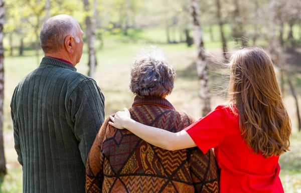 back of 3 adults and younger woman on the right holding arm around older woman in the middle