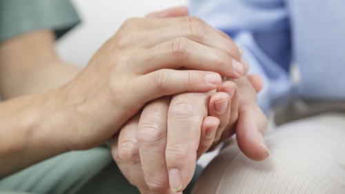 nurse holding resident's hand