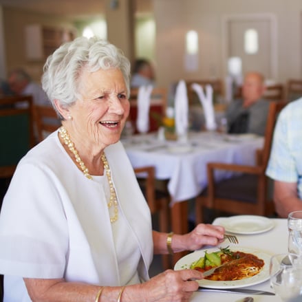Senior Woman Eating in Community Dining Hall