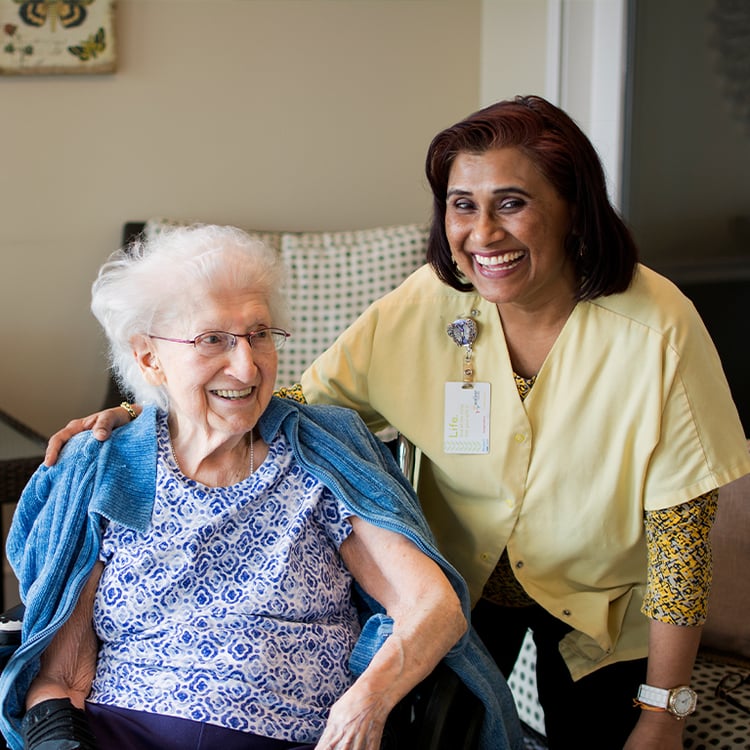 senior sitting next to standing caretaker