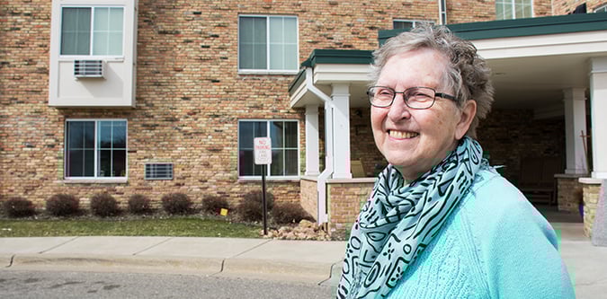 Elderly woman stands in front of Walker Methodist Lyndale entrance