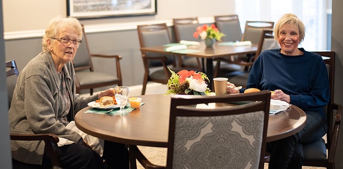 Two women eat meal at dining room table