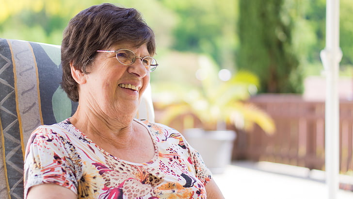 grandma sitting in chair and smiling at someone nearby